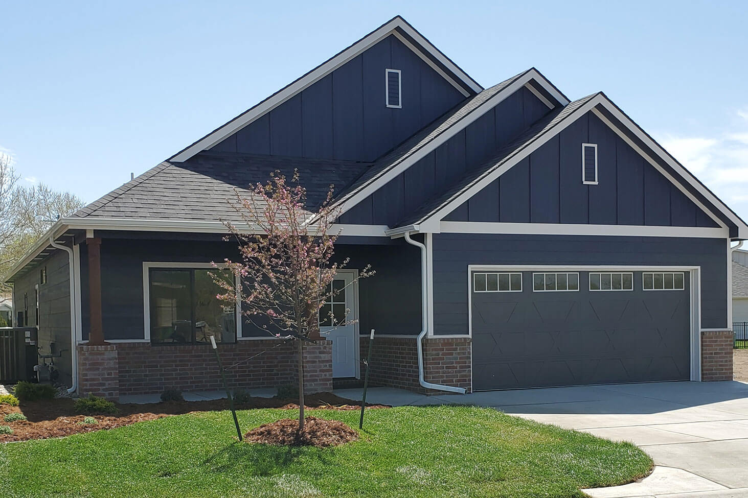 A brand-new, dark blue patio home with a two car garage.