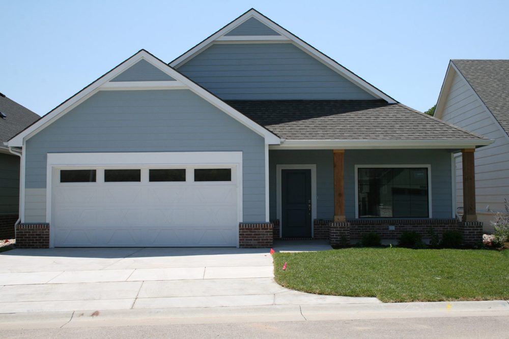 A brand-new, light blue patio home with a two car garage.