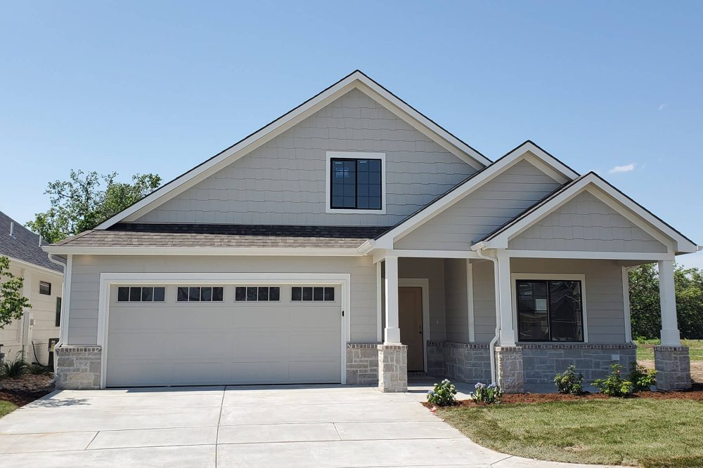 A brand-new, gray patio home with a two car garage and stone accents.